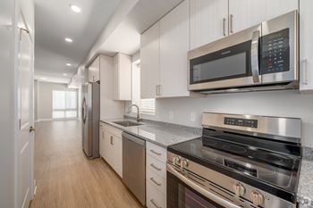 A modern kitchen with stainless steel appliances and wooden floors.